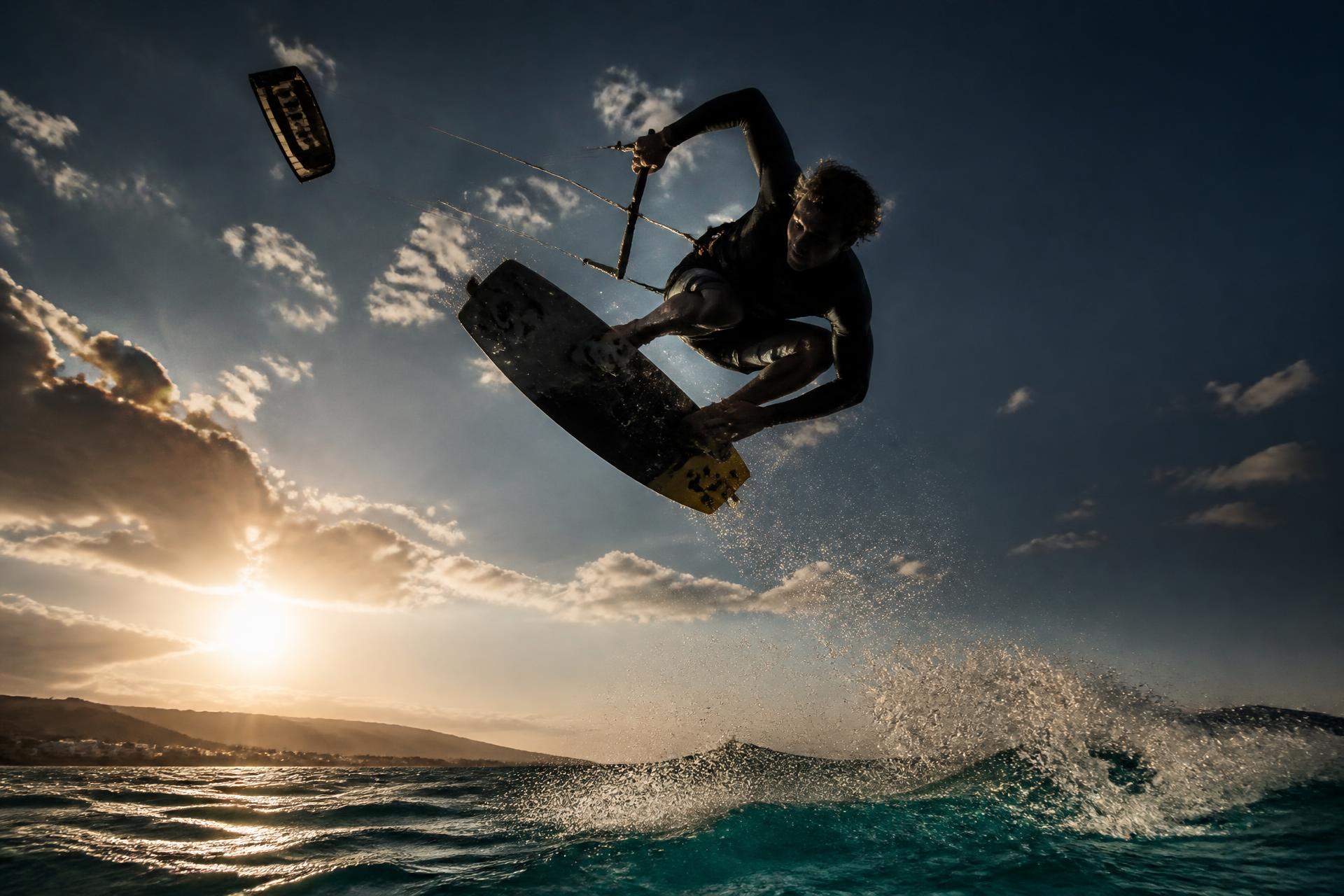 Gün batımında büyük hava atlayışı yapan kitesurfçü
